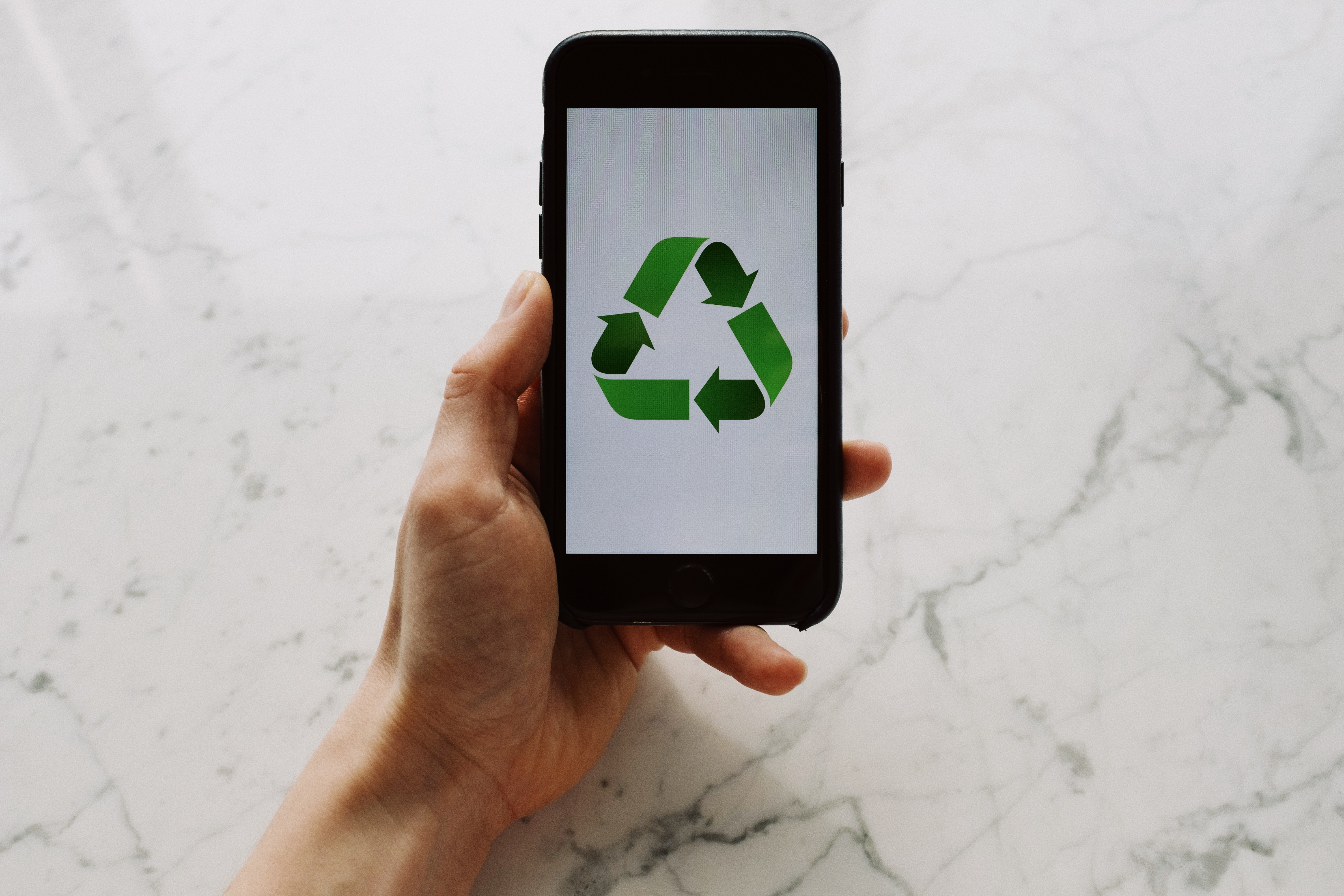 hand holding a phone with the recycle symbol on the screen